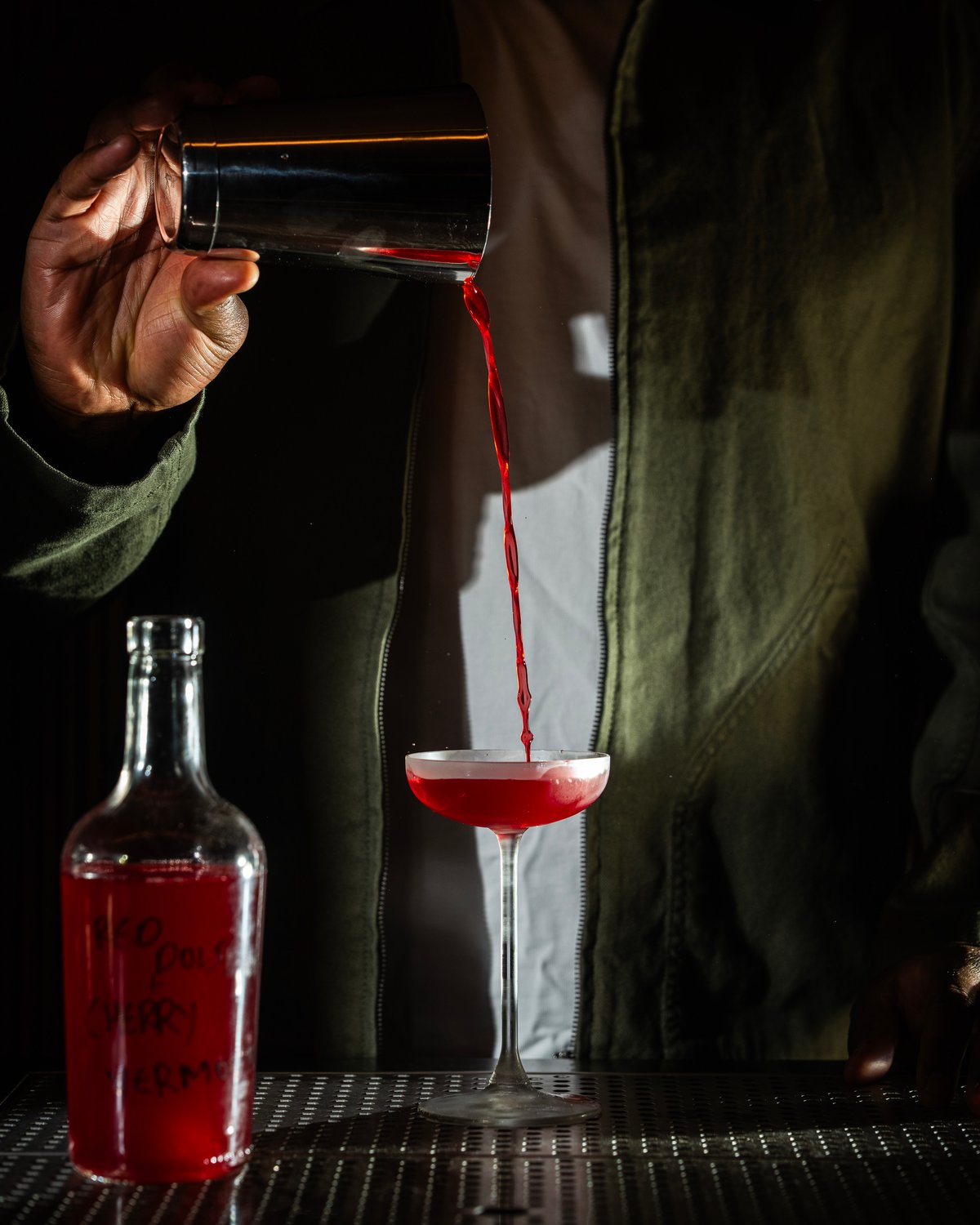 A cocktail being poured from a cocktail shaker at cato